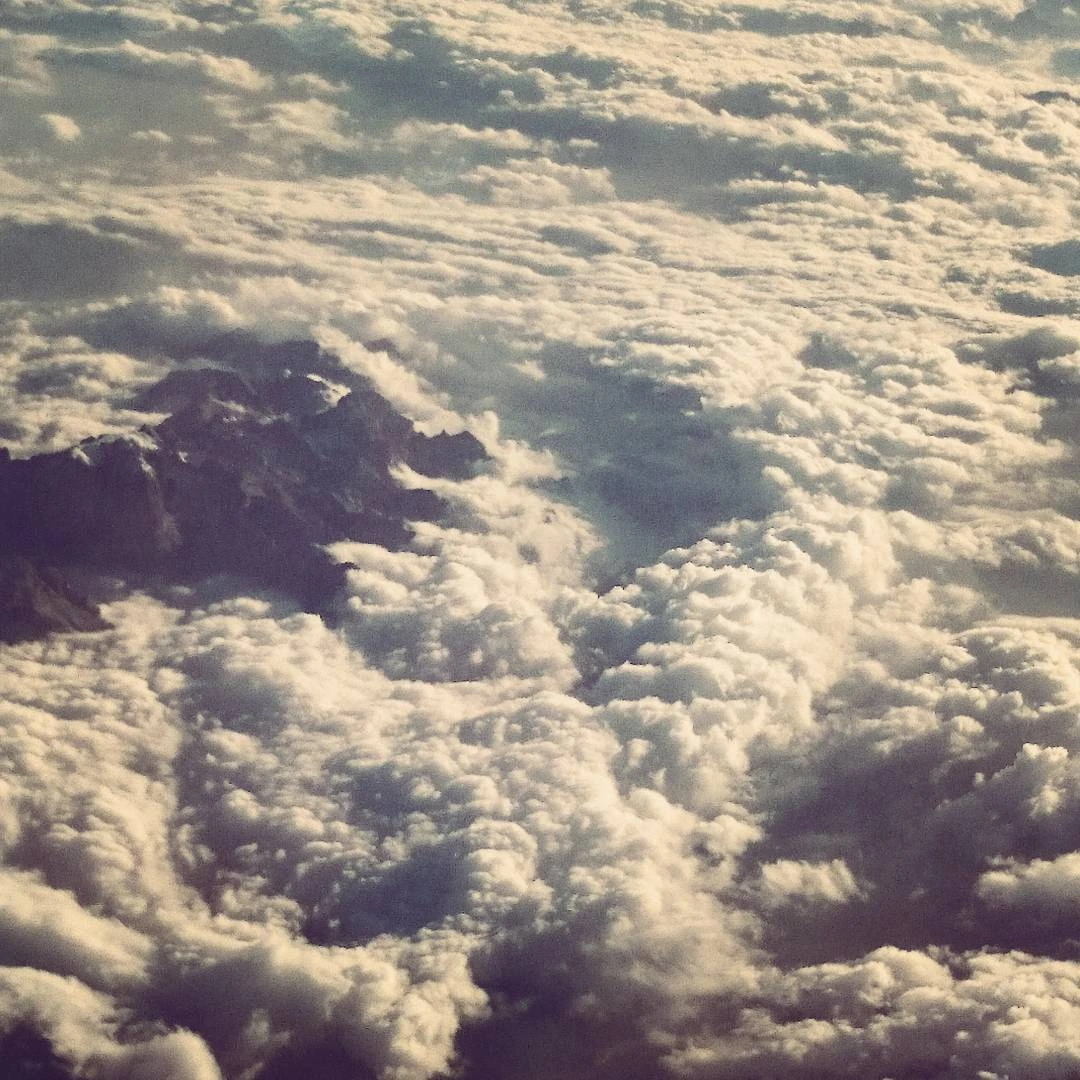 Dark mountain peaks emerging through a dense layer of clouds